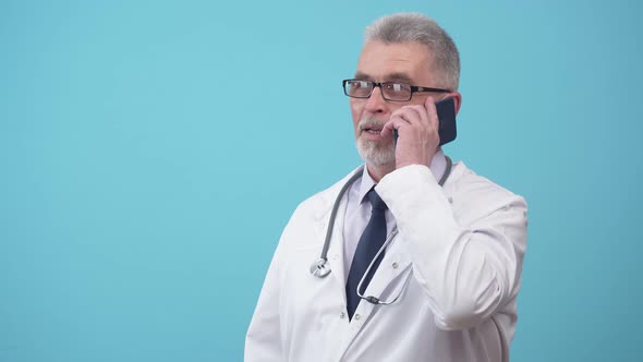 Adult Doctor Talks on the Phone and Takes Off Glasses