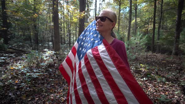 Pretty blonde mature woman holding a flag up to her and smiling.