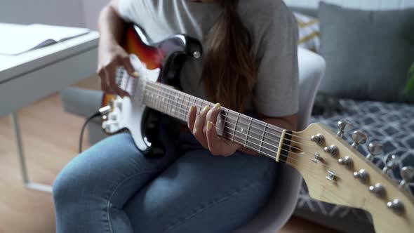 Young woman playing electric guitar at home