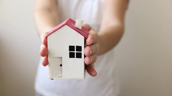 Woman Hand Holding Toy Model House Isolated on White Background