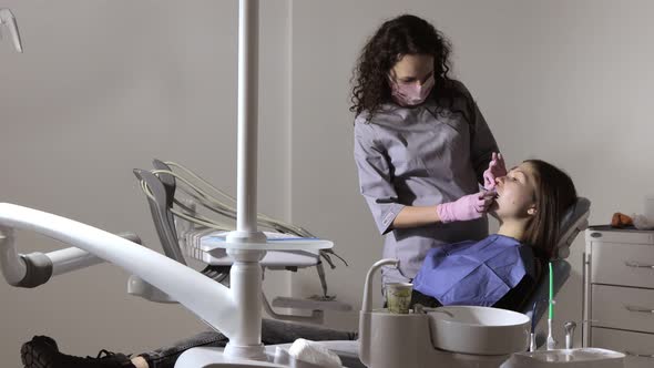 The orthodontist using dental impression tray on woman teeth