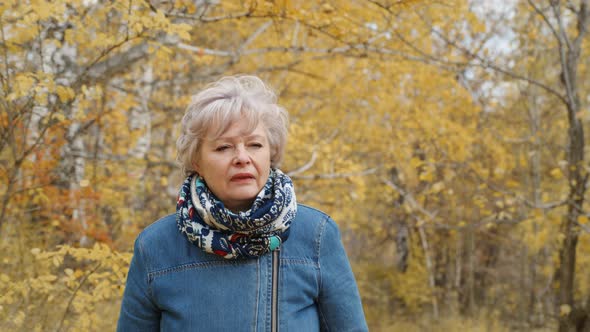 Elderly Woman Walks in the Park in Autumn and Relaxes.