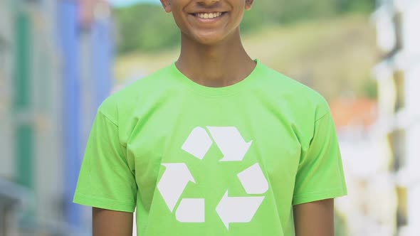 Boy in shirt with recycle sign smiling into camera