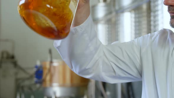 Male worker examining liquor in flask 4k