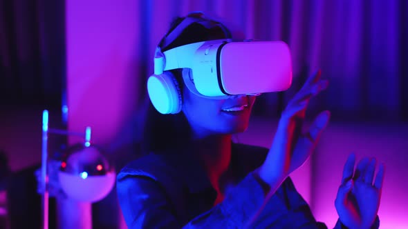 Young asian woman is using virtual reality headset. Neon light studio portrai