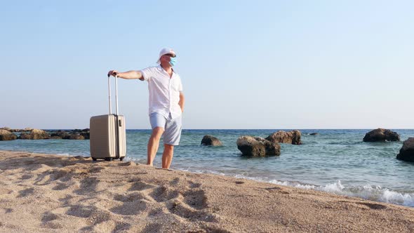 Man in Protective Mask and Summer Clothes, Enjoys Warm Sunbeams, By the Sea, Beach with Palm Trees