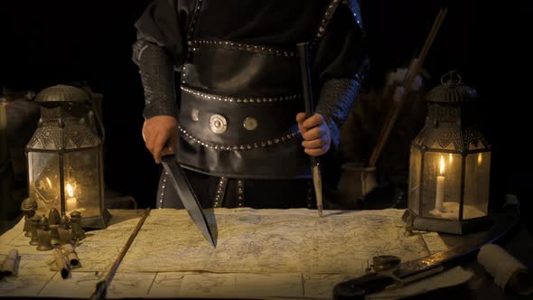 Commander working on map with sword in hand. alt
