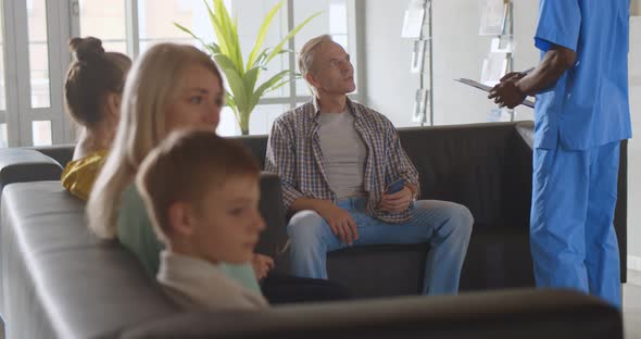 Nurse Inviting Mature Male Patient in Doctor Office in Clinic