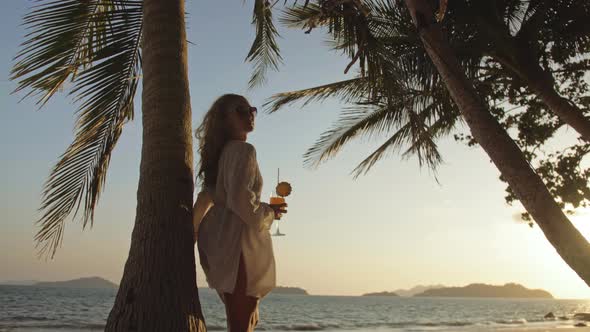 Woman Drinking Pineapple Cocktail Pina Colada Near Palm Tree in White Shirt Sunglasses