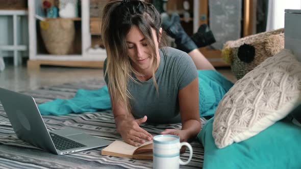 Happy casual beautiful woman working on a laptop laying on the floor in the house