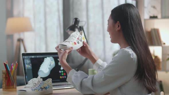 Female Footwear Designer Holding And Looking At The Colourful Pattern Sneakers While Designing Shoe