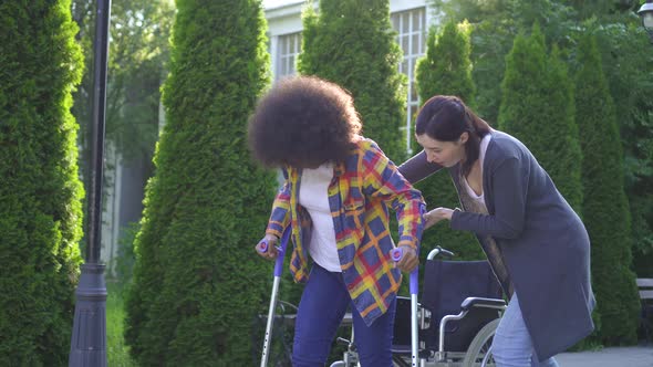 African Woman with an Afro Hairstyle Disabled in a Wheelchair in Rehabilitation Learning To Walk