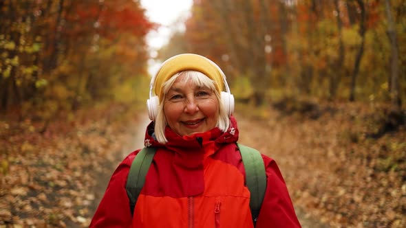 Cheerful Active Mature Happy Woman in Stylish Clothes Walking Along Having Fun Outdoors in City Park