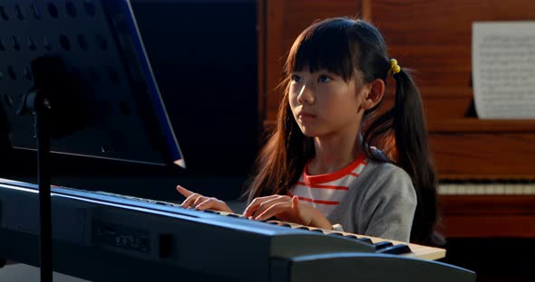 Schoolgirl learning electric piano in music class 4k