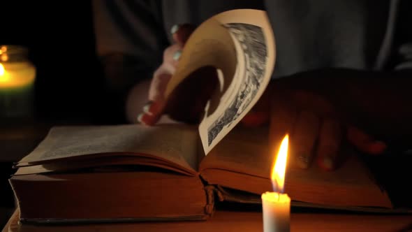 Girl Reads an Old Book By Candlelight in the Evening