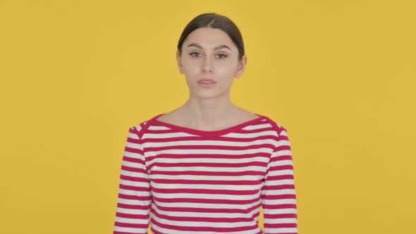 Spanish Woman Shaking Head in Rejection on Yellow Background