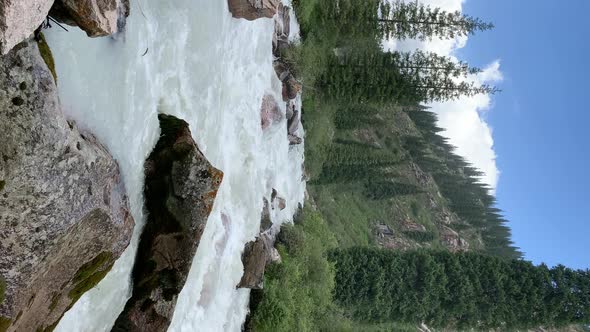 A Beautiful Stormy Mountain River of Milky Hue Flows Rapidly Among