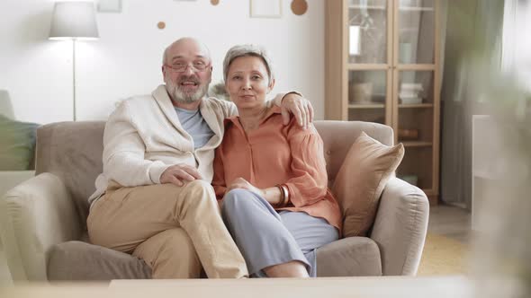 Two Seniors Sitting on Sofa and Speaking