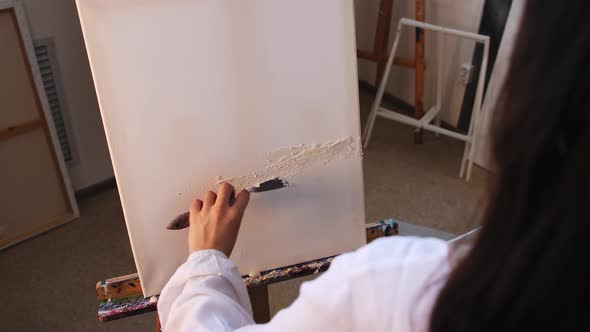 Art Studio  Young Woman Artist Putting a Primer on the Canvas