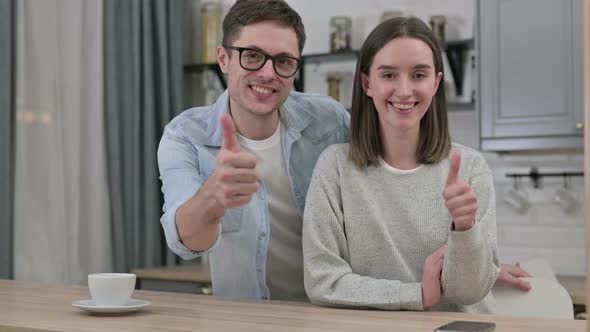 Happy Young Couple Doing Thumbs Up in Living Room