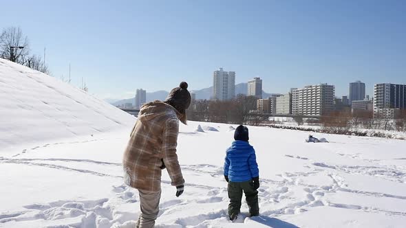 Asian Mother And Her Son Playing Snow Together In The Park 