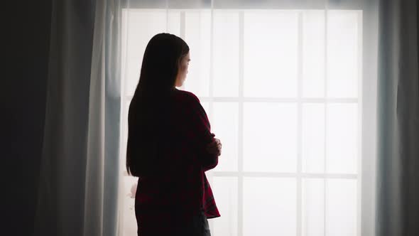 Silhouette of Woman with Long Hair Stands Near French Window