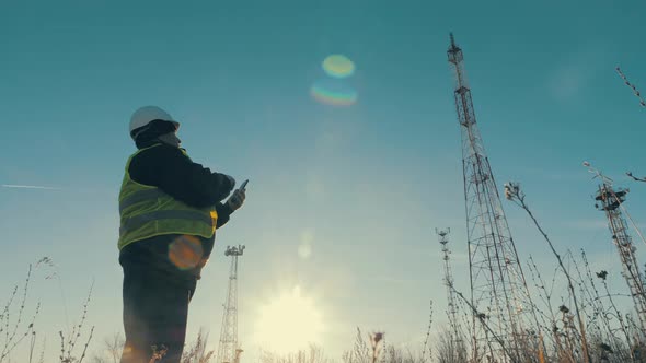 Silhouette Engineer Working on Satellite Dish Telecom Network on Telecommunication Tower in Sunset