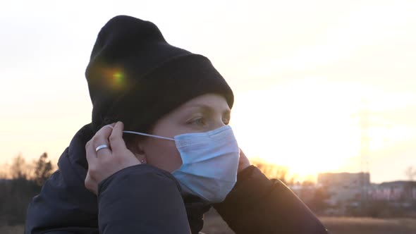 Young Woman Putting Off Face Mask And Breathing Deep Outdoors. 