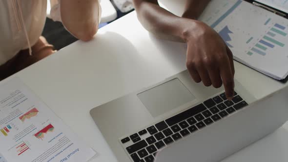 Hands of two diverse female colleagues poiting at laptop and discussing in office