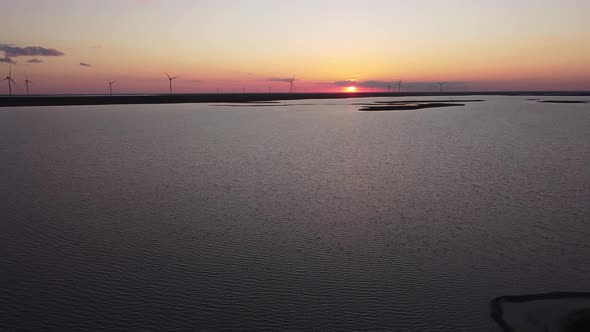 Aerial View of Wind Turbines and Agriculture Field Near the Sea at Sunset