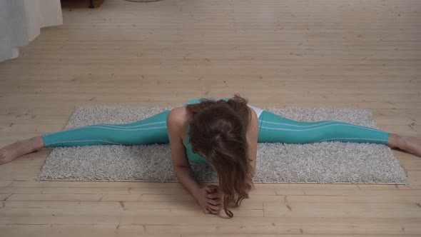 Young Flexible Woman Sits on a Twine