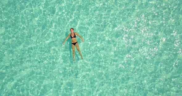 Aerial drone view of a woman floating and swimming on a tropical island.