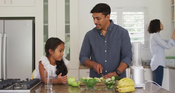 Hispanic father teaching smiling daughter cooking in kitchen
