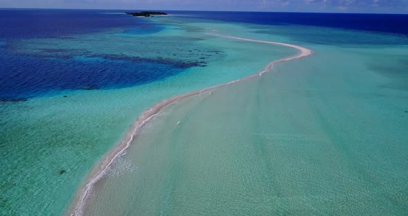 Wide above travel shot of a paradise sunny white sand beach and blue sea background in 4K