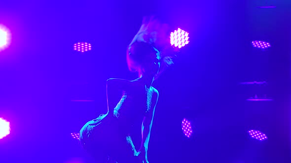 Passionate Young Brunette Go Go Dancer Incendiary Dancing in a Dark Studio. Silhouette of a Female