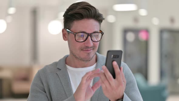 Portrait of Focused Middle Aged Man Using Smartphone 