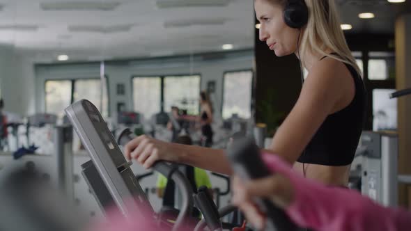 Sporty woman listening to music and exercising at gym