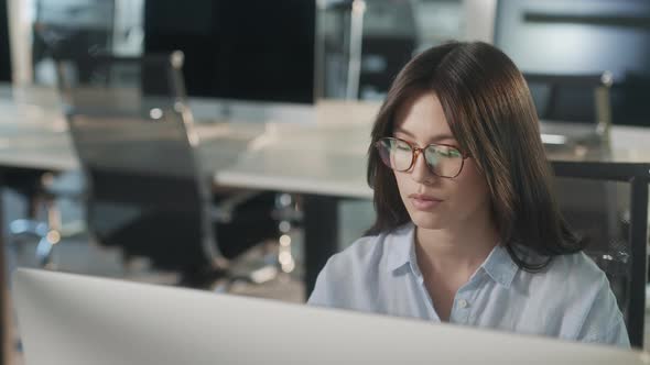 Young Asian Marketing Specialist Working on Laptop Computer in Busy Creative Office Environment