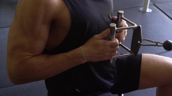 Muscly man in home gym exercising close grip cable lat row seated