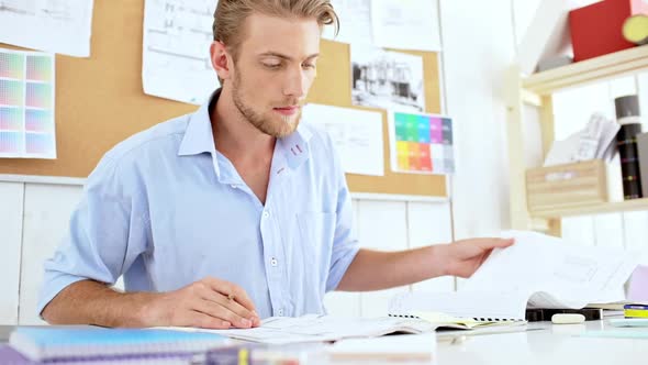 Successful Architector Looking Through Drawings Sitting at Workplace Slow Motion