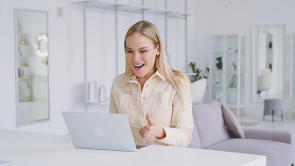 Successful woman typing on laptop in white room. Young woman receiving good news message