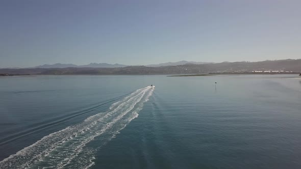 Following aerial as motorboat turns around in Knysna Lagoon, S Africa