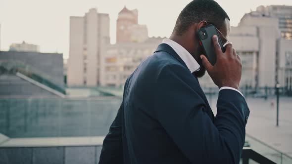 Serious African Businessman Talking with Partners Via Cell Phone Moving Down on Staircase Outdoors