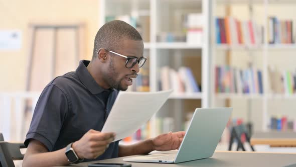 African Man Having Loss Working on Laptop with Documents