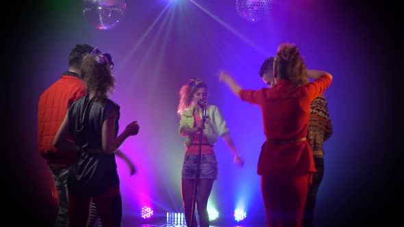 Girl Performing on Stage As Audience Dances in Smoke Studio