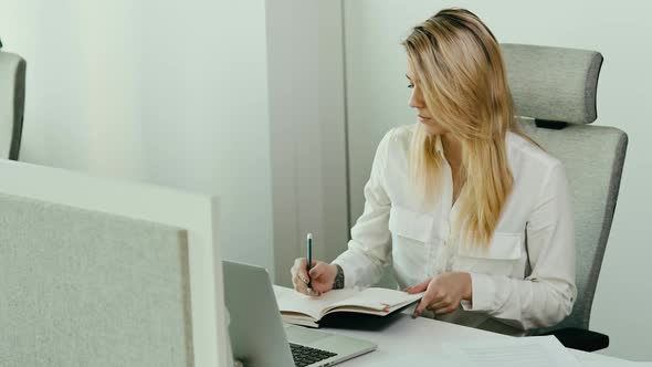 Beautiful young businesswoman looks at the calendar