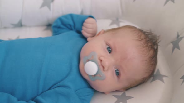 Rocking Lovely Little Kid Sucking Dummy in Cocoon in Crib