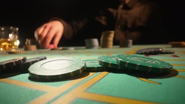 Unrecognizable Male Gambler Makes Bets While Sitting at Roulette Table in Casino