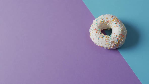 Video of donut with icing on purple and blue background