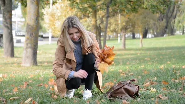 Beautiful Blonde Woman Collects Fallen Leaves
